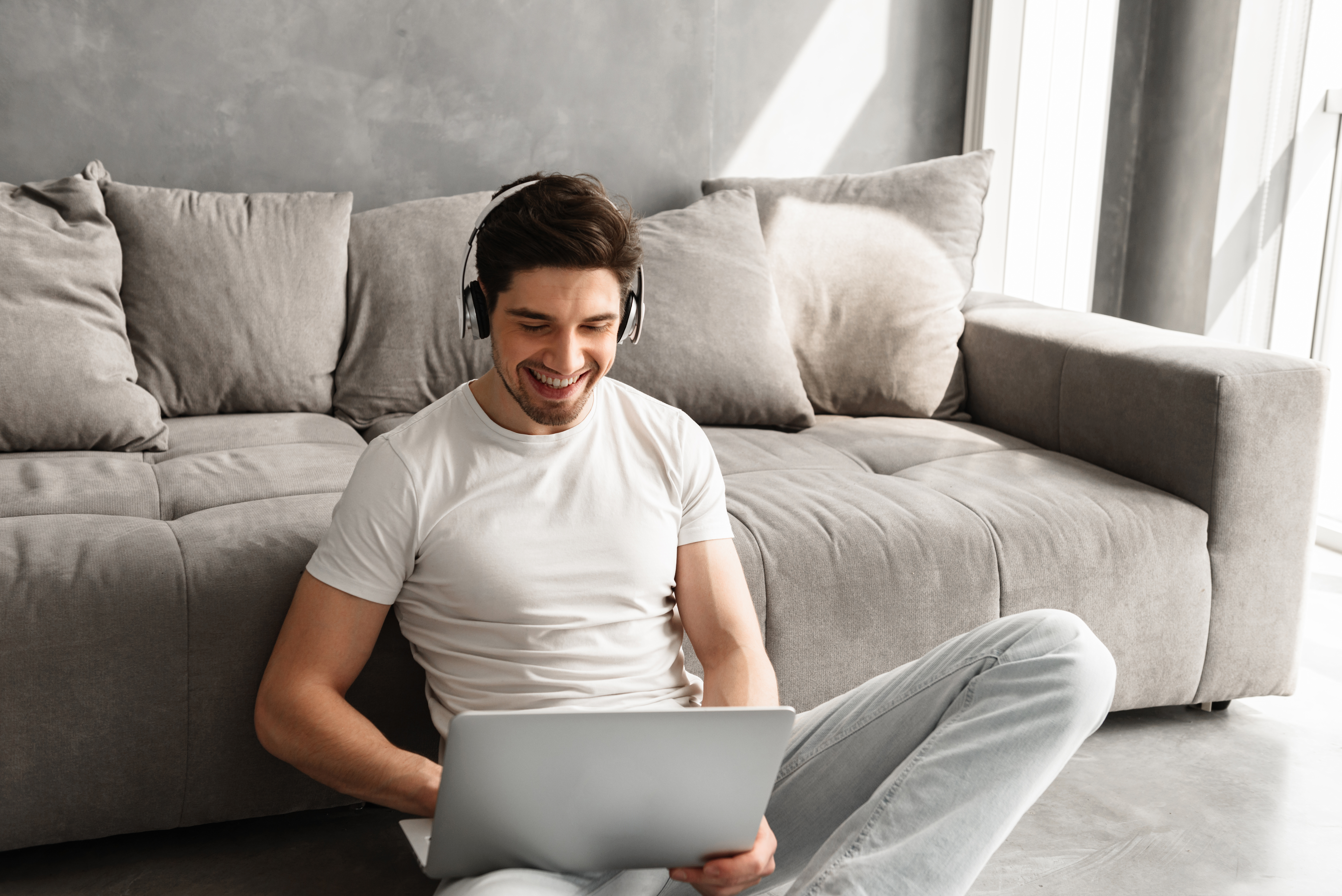Happy guy with dark hair sitting on floor indoor, and listening