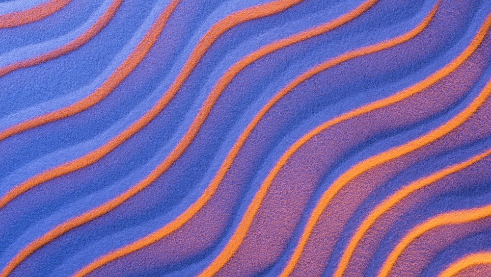 Background image of neon coloured waves of sand.