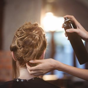 Hair being sprayed with hairspray in salon.