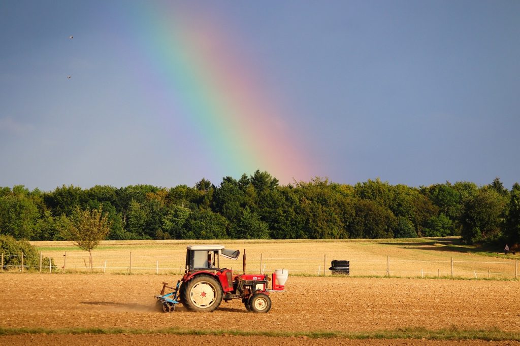 Tractor in field with a rainbow sky