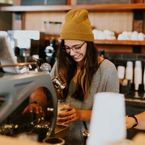 person wearing a hat making a coffee
