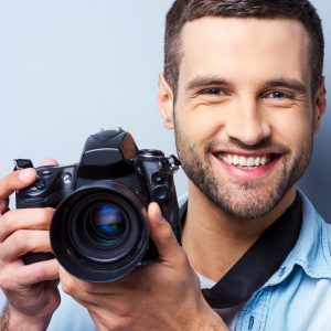 Smiling man holding digital camera.