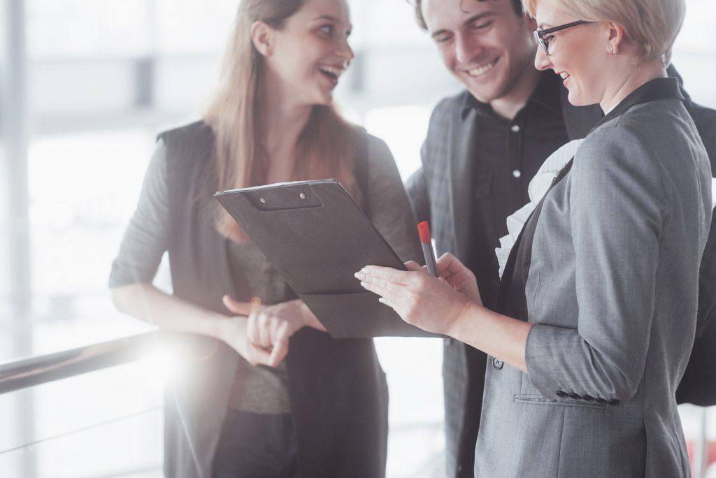 Three business people looking at clipboard.