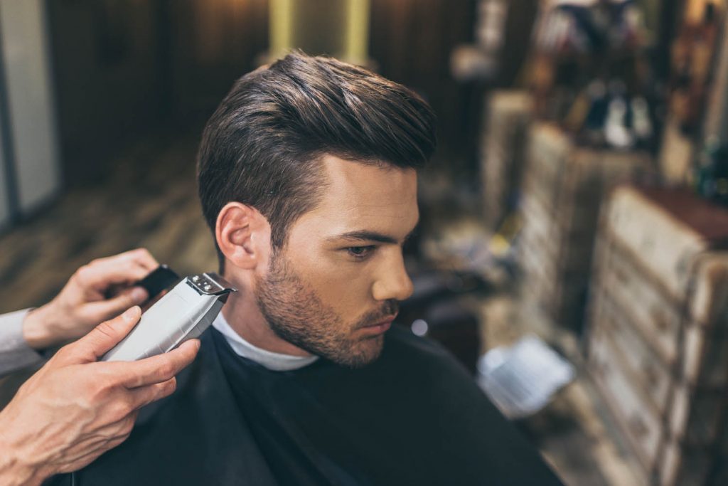 Man having hair cut with clippers in barbers.