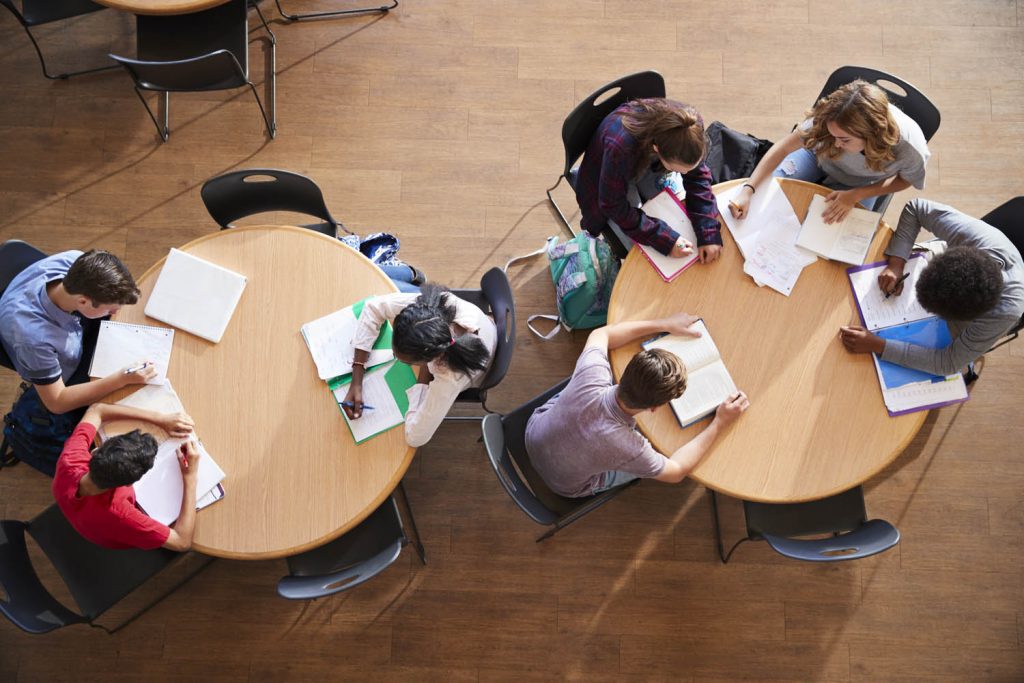Overhead photo of students at round tables studying.