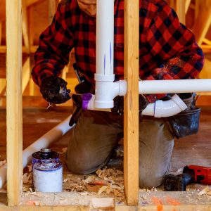 Plumber working on piping in new build