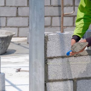 Person using trowel to lay concrete bricks