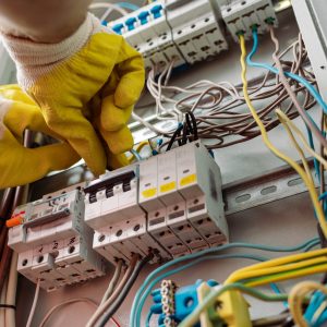 Hands in safety gloves working on fuse box