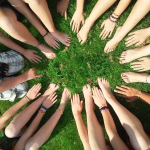 a circle of feet and hands on the grass
