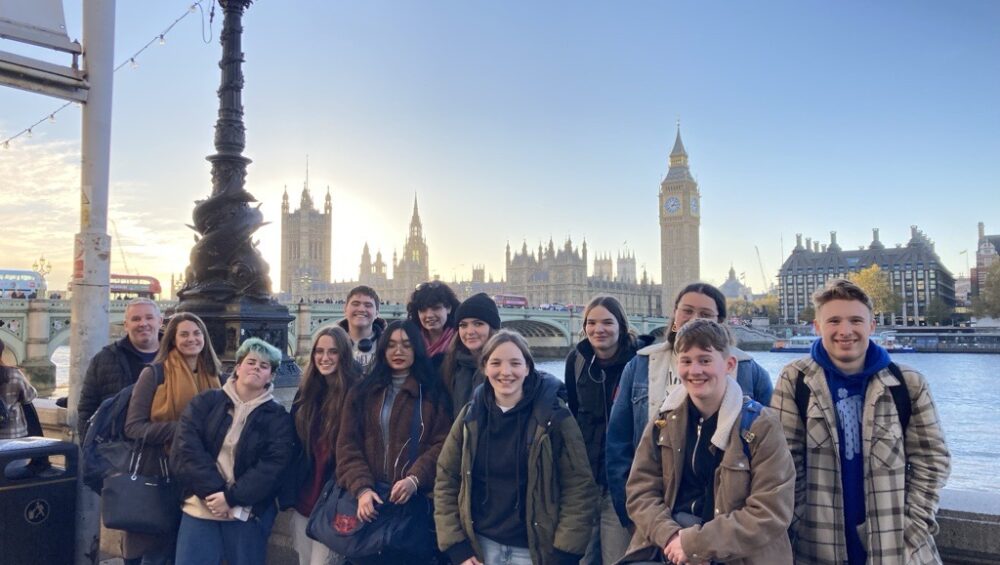 Group of students standing by the Thames with Westminster in background.