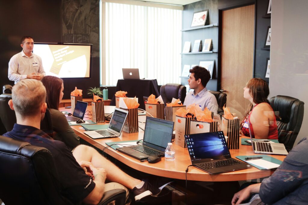 man conducting meeting with delegates around table on laptops