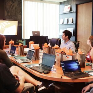 man conducting meeting with delegates around table on laptops