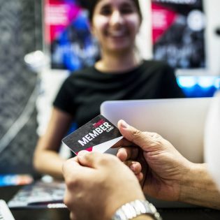 hands holding a membership card with person in background