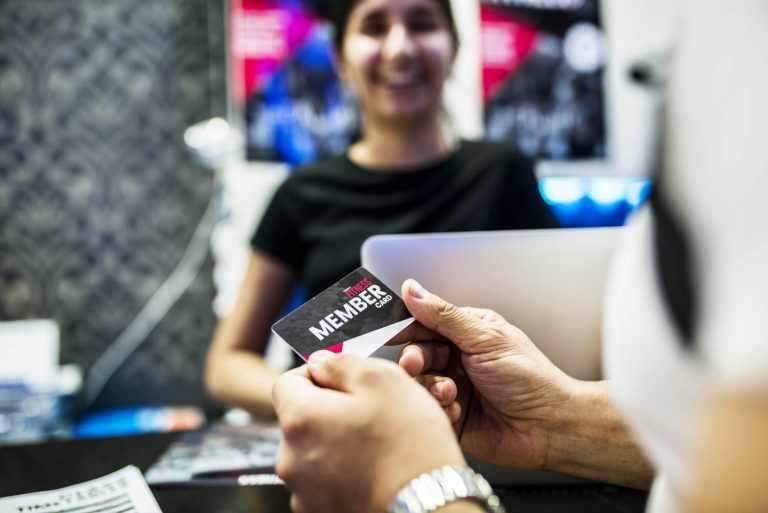 hands holding a membership card with person in background