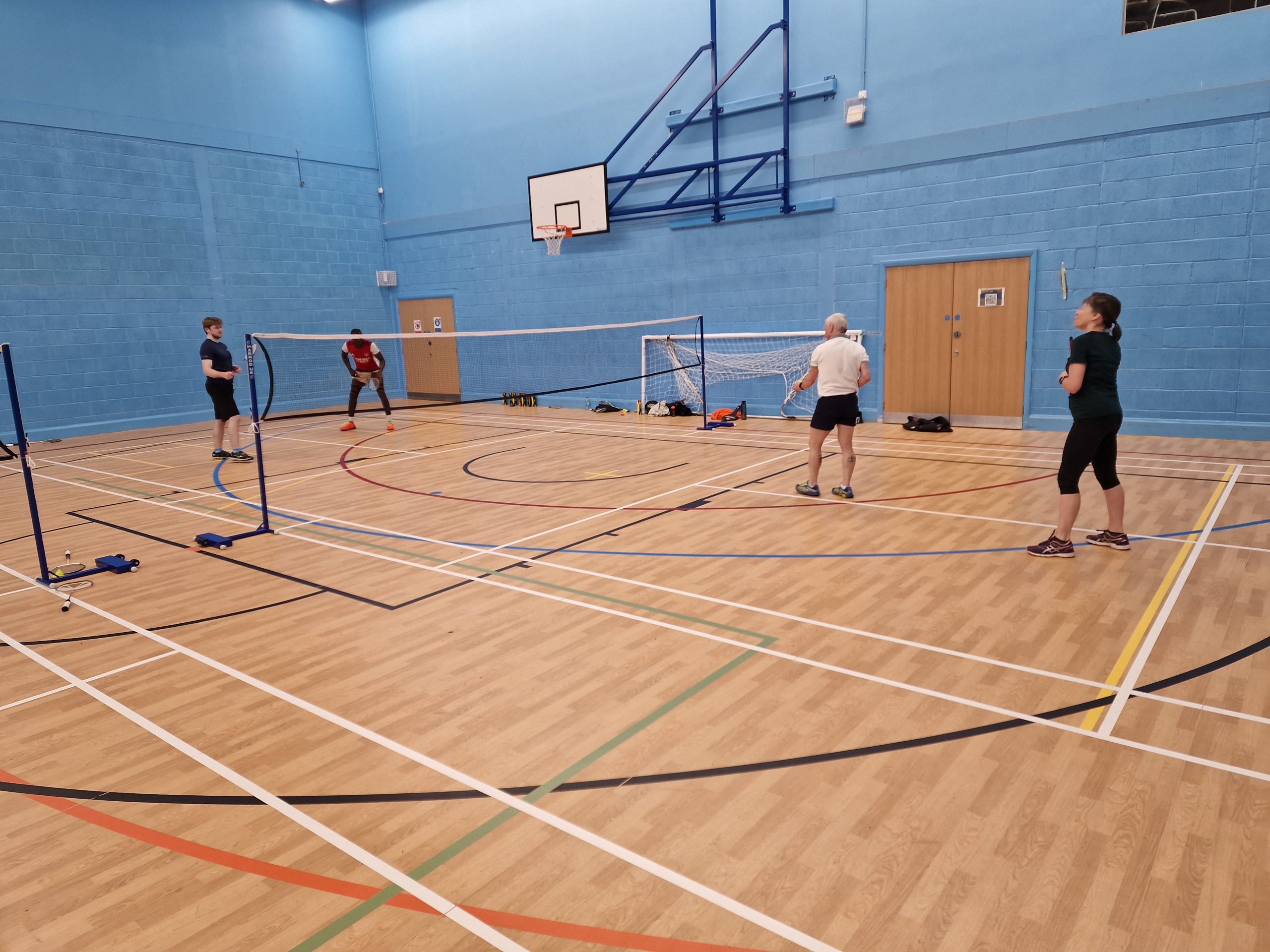 People in sports hall playing badminton
