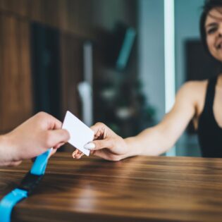 Cheerful woman talking to employee on reception taking card for access in gym