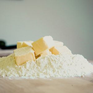 Cubes of butter on a mound of flour on wooden surface.