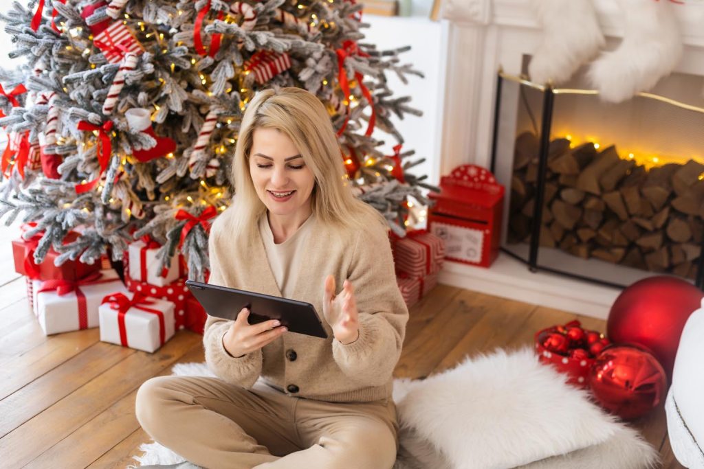 woman with tablet on the background of a Christmas tree.
