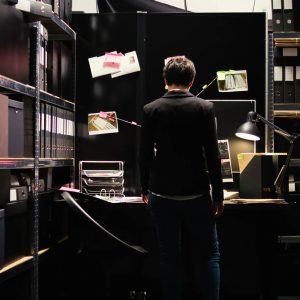 Back of a person in a dark room surrounded by files.