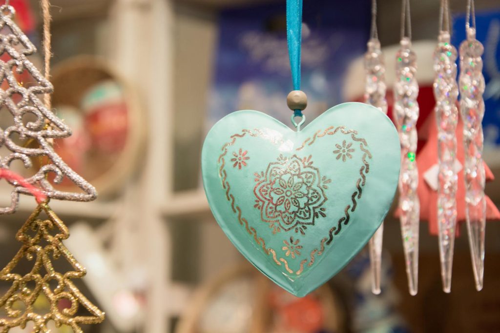 Christmas blue heart in fair kiosk with red handcrafted xmas decorations. Close up.