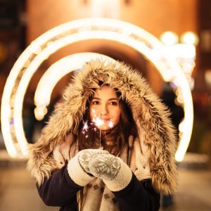Woman wearing coat and holding sparkler
