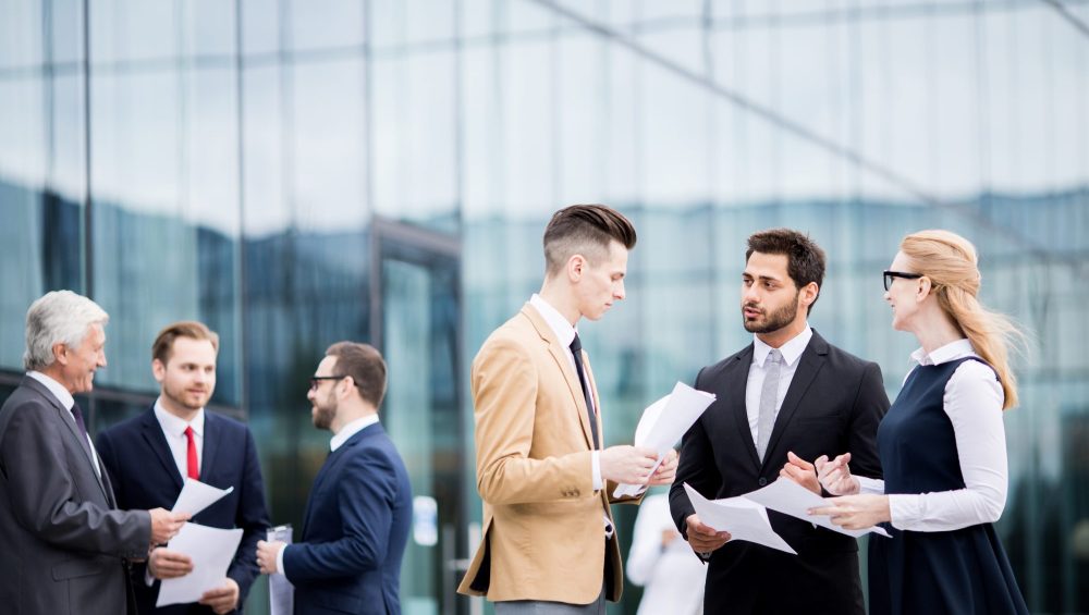 Groups of business people talking outside office building.