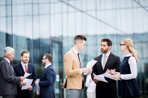 Groups of business people talking outside office building.