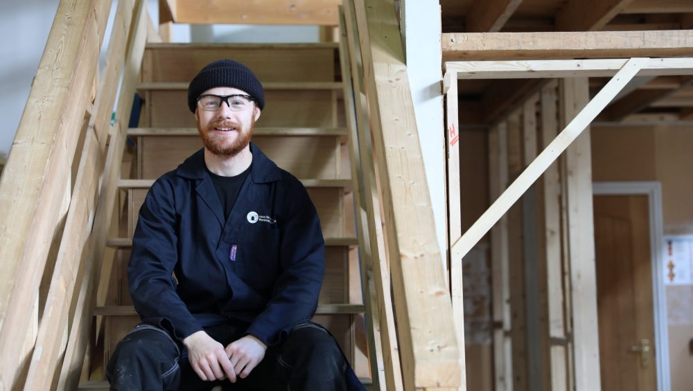 Conor sitting on wooden stairs.