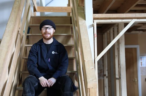 Conor sitting on wooden stairs.