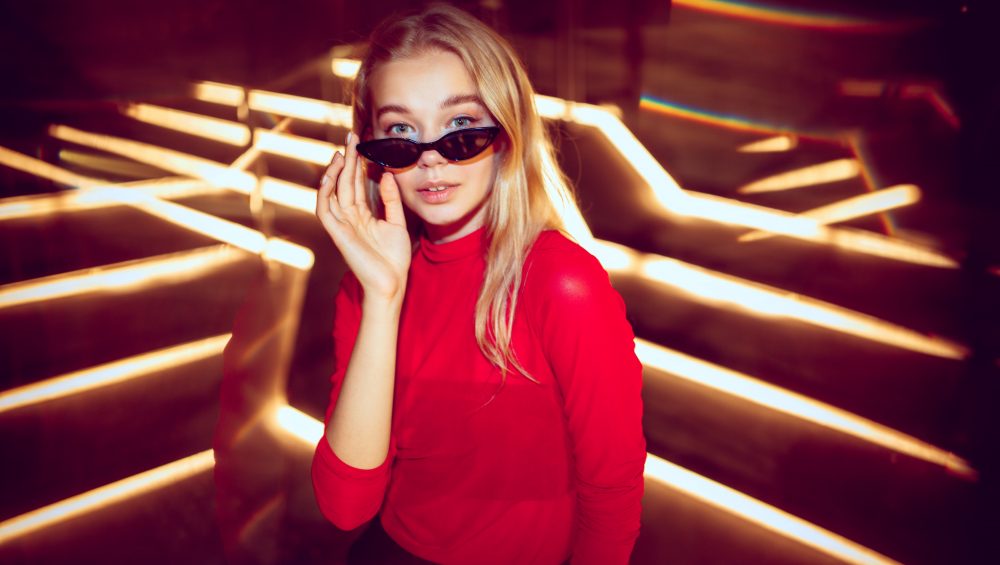 Woman touching glasses with neon lighting.