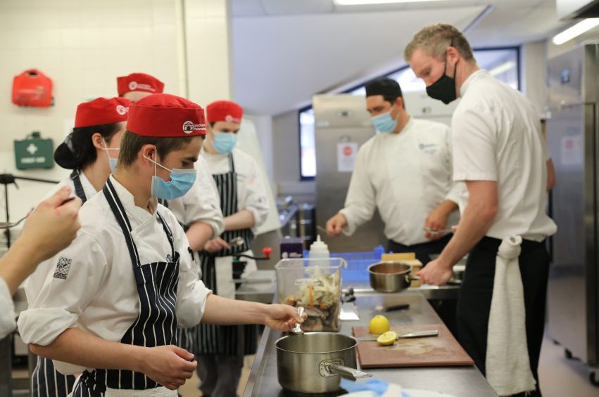 Two Chefs teaching catering students.