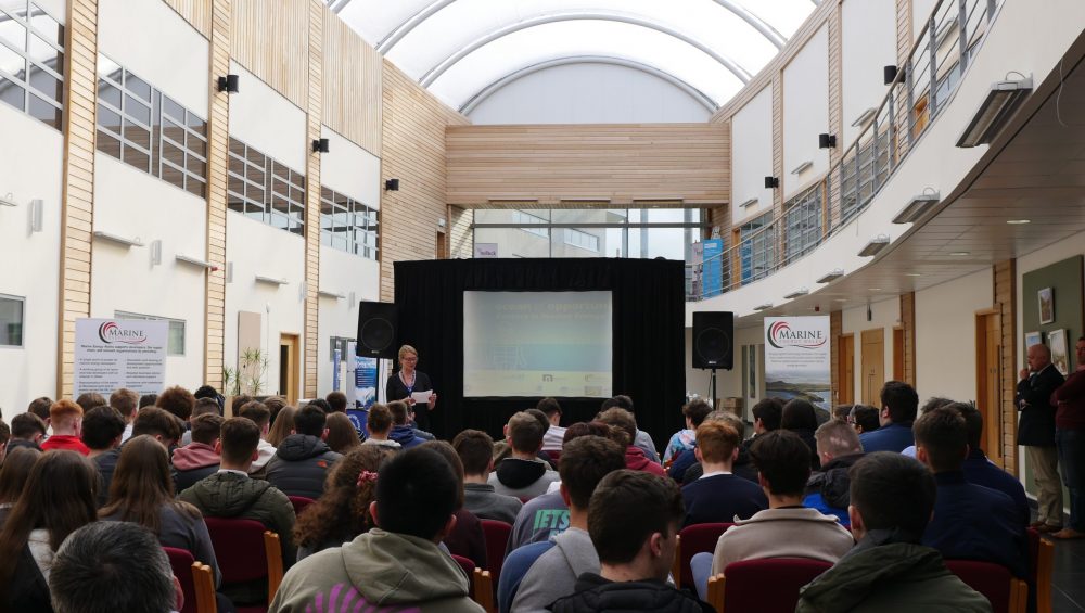 Person talking to group of seated students at Bridge Innovation Centre in Pembroke Dock.