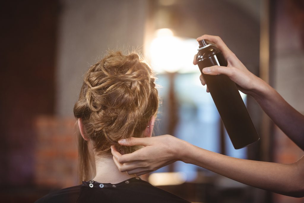 Hair being sprayed with hairspray in salon.