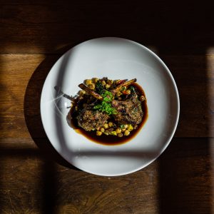 Plate with cooked food, lamb chops with chickpeas.