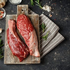Two beef fillets on chopping board.