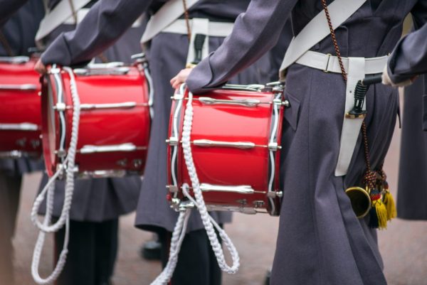 Cropped image of red military drums being carried by soldiers.