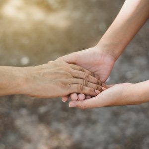 Cropped image of young hands holding an older hand.