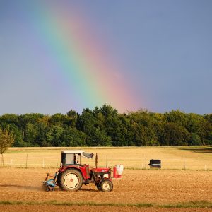 Tractor in field with a rainbow sky