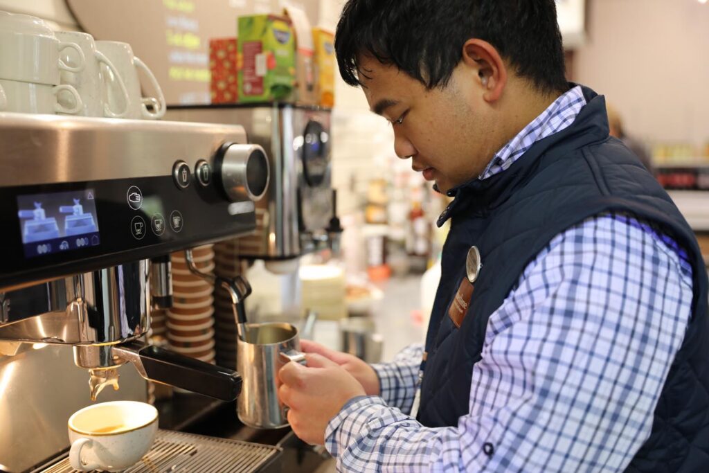 Student making coffee at machine.