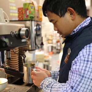 Student making coffee at machine.