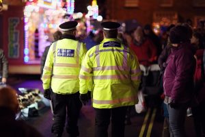 British community officers walking in busy street at night.