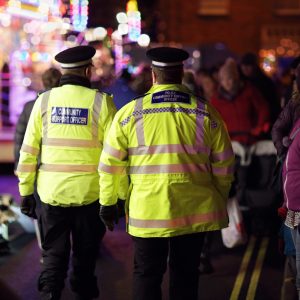 British community officers walking in busy street at night.