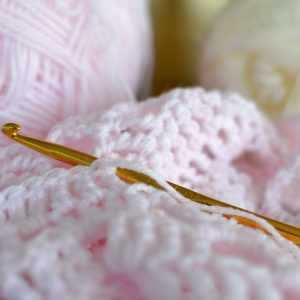 Pink wool and crochet needle.