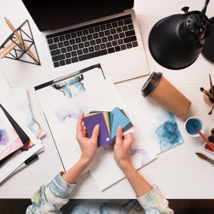 Cropped image of designer at desk looking at colour samples.