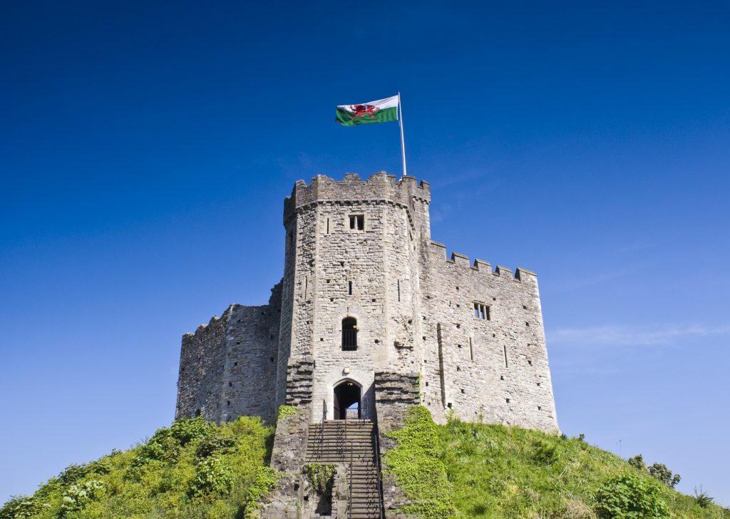 Castle on hilltop flying Welsh flag.