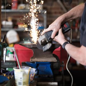 Person grinding an anvil in workshop.