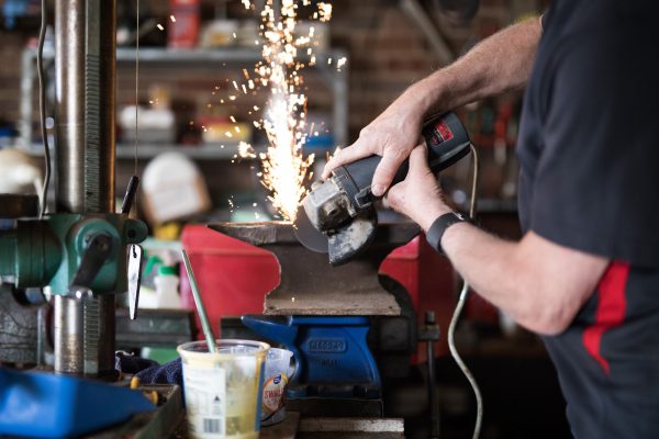 Person grinding an anvil in workshop.