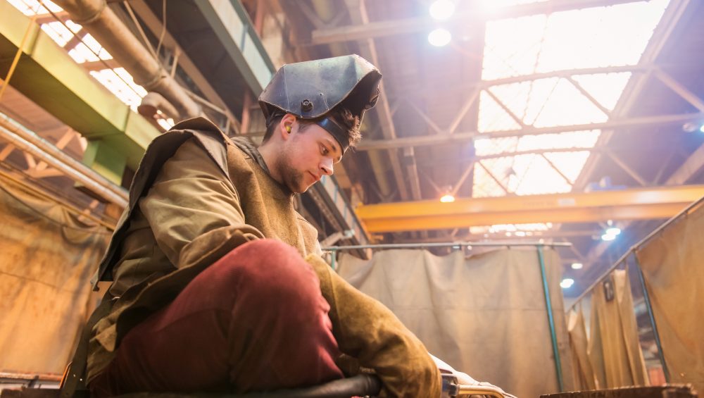 Welder sitting on floor about to start work.