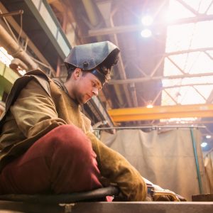 Welder sitting on floor about to start work.