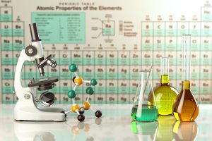 Microscope and glass flasks in front of periodic table.